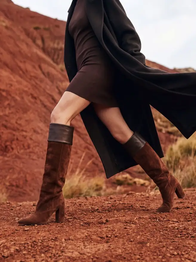 Mascaró campaign image made with Ai: suede knee boots walking on red earth by the sea